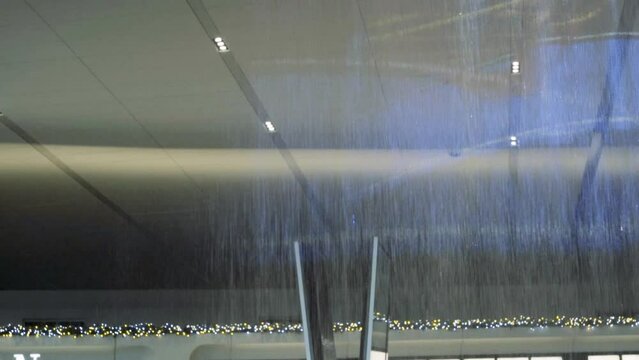 Tilt down water falling slow motion ceiling fountain LGA NYC Queens