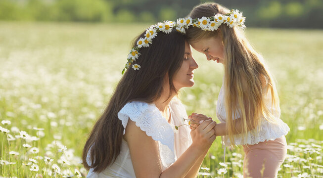 Banner with beautiful mother and daughter in flowers wreath spend time together and walking in chamonile field. Happy mothers day. Love between mom and child.