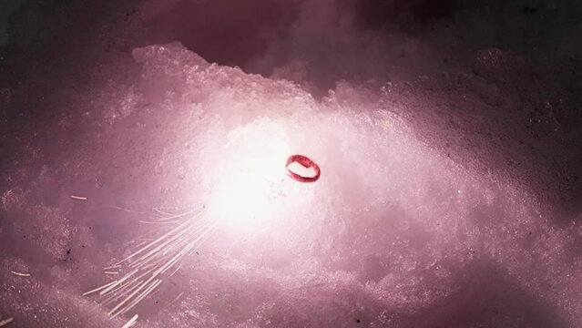 Small failed fire cracker burning in the snow and fade out