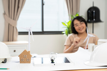 Portrait of a young Asian woman studying environmental green energy of a solar wind turbine at home in her home.