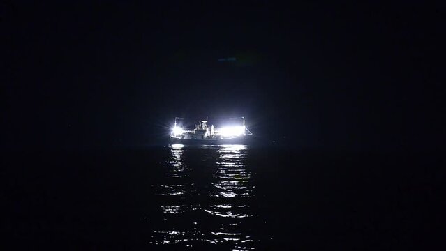 밝은 불을 킨 오징어잡이 배가 어두은 밤 바다에 홀로 떠있다