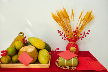 Tray with fresh fruits, traditional rice cake and lucky money envelopes on table decorated for Tet