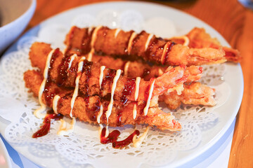 Fried shrimp tempura skewers with drizzled sauce.