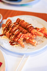 Fried shrimp tempura skewers with drizzled sauce.
