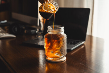 Iced coffee in a mug on the computer table