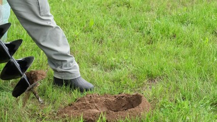 Drill the ground. The man drilling the land hole. Borer for the fence installation, planting tree, bushes. Bore tool. Portable manual earth auger for prepare the soil for planting shrubs or trees