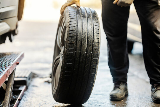 Cropped picture of auto mechanic with car tire.