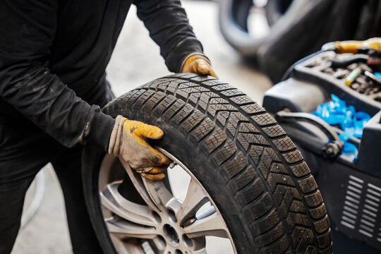 Close up of mechanic's hands holding car wheel at vulcanizing workshop.