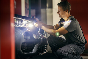 Side view of a car wash worker polishing car at station.