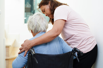 Asian senior woman on wheelchair with caregiver help support walking down the stairs prevent...