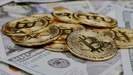 Close up of metal shiny bitcoin crypto currency coins on US dollar bills. Electronic decentralized money concept.