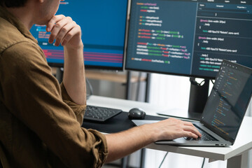IT developer working online software development on pc monitors at modern home office on coding...