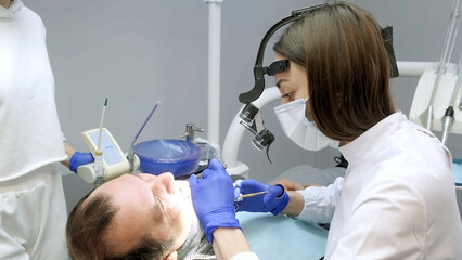 A man having a consultation and treatment with a female dentist in a professional dental clinic....