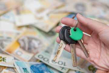 Kupować mieszkanie, klucze w dłoni na tle rozmytych pieniedzy