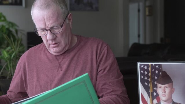 Man looks at scrapbook belonging to his military son killed in action