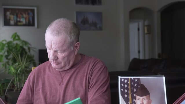 Retired military man looking at a scrapbook of his life of military service