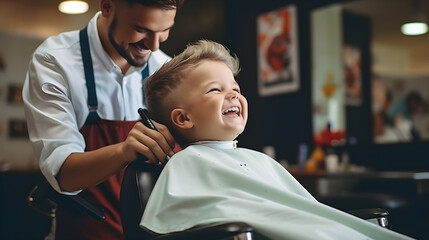 A little boy gets a haircut from a barber in the salon - obrazy, fototapety, plakaty