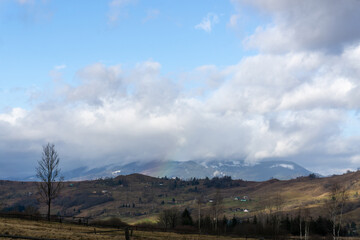 Snowless winter, rainbow in mountains