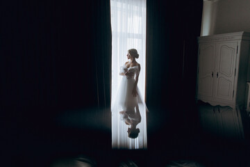 Morning of the bride, where she gets ready for a wedding in a beautiful luxury hotel in a robe with stylish hair and makeup, and then puts on a white wedding dress.