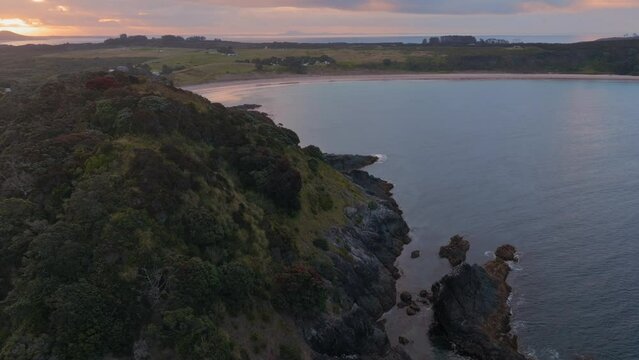 Aerial: Ocean and beach in Matai Bay at sunset. Bay of Islands, Northland, New Zealand.