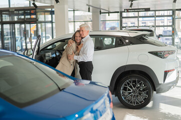 Mature Caucasian couple hugging with happiness while buying a new car. 