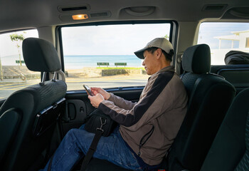 Man in the shuttle bus looking at his smartphone. Passenger gets ready to go to the airport.