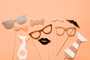 Photo booth props glasses, mustache, lips on a pink background flat lay. New trending PANTONE Peach...