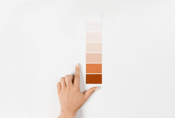 Hand holding Color samples palette design catalog. New trending PANTONE Peach Fuzz colour of 2024...