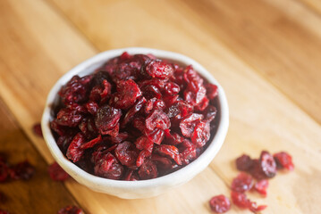 dried cranberries in white ceramic bowl on wooden table.