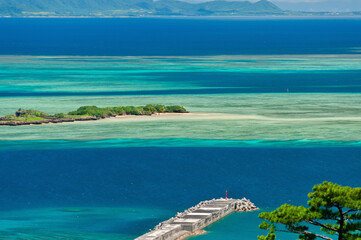 Amazing view of gradient blue sea, green islet, long pier. Iriomote Island.