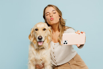 Young cool owner woman with her best friend retriever wear casual clothes do selfie shot on mobile cell phone hug dog isolated on plain pastel light blue background studio Take care about pet concept