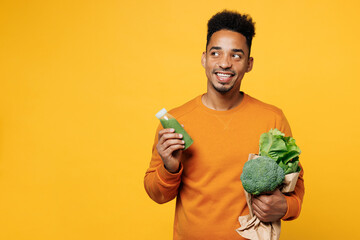 Young happy man wear casual clothes hold juice green smoothie as detox diet, greenery herbs look...
