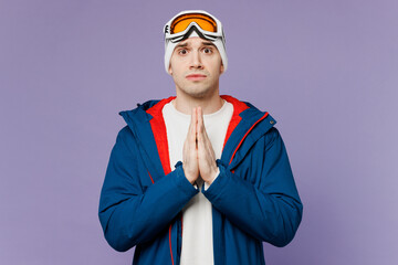 Skier man wear warm blue windbreaker jacket ski goggles mask hold hands folded in prayer gesture beg spend extreme weekend winter season in mountains isolated on plain purple background Hobby concept