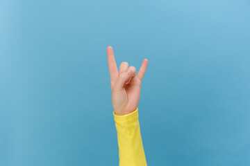 Close up of female hand showing Rock and Roll sign, posing isolated over plain blue color...