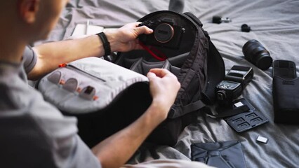 A professional photographer checks and collects the camera and equipment in a special backpack. The view from over the shoulder. 
