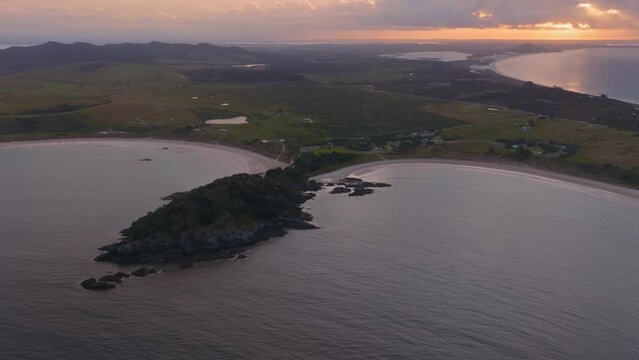 Aerial: Ocean and beach in Matai Bay at sunset. Bay of Islands, Northland, New Zealand.
