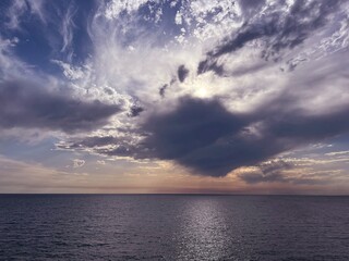 Sunset sky clouds over sea glittering water at evening.
