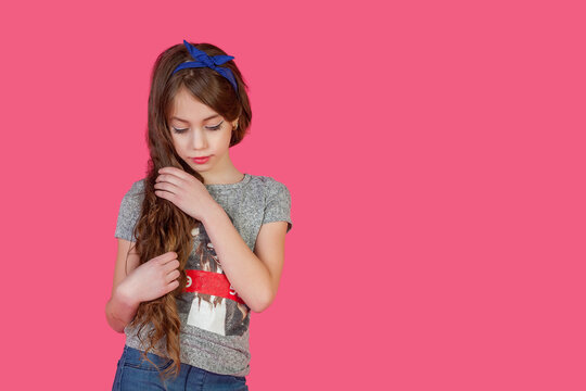 Portrait of unhappy little cover girl in casual wear posing at pink isolated, sad look. Bored emotional kid lady model 9 year old, studio shot. Child negative emotion concept. Copy ad text space
