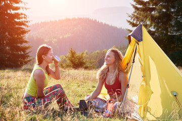 Two women hikers camping in mountains. Female friends having break in campsite. Young, positive...