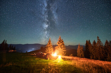 Night camping in mountains under starry sky. Tourist tents in campsite under beautiful sky full of...