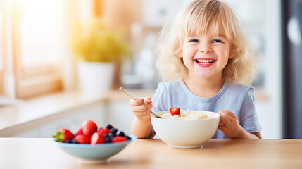 Smiling adorable child having breakfast eating oatmeal porridge