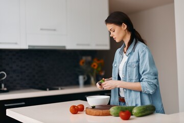 Cooking up a Healthy Lifestyle: Young Female in a Modern Kitchen, Preparing Fresh Vegetarian Salad with Green Ingredients
