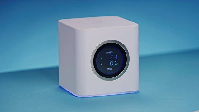 LCD display high end wireless internet wifi router is showing transfer speed in kilobits and megabits per second as data is uploaded thru network. Cinematic hiqh quality product shot, blue background.