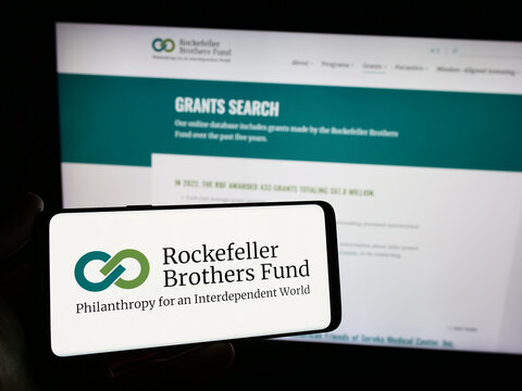 Stuttgart, Germany - 12-29-2023: Person holding smartphone with logo of US foundation Rockefeller Brothers Fund (RBF) in front of website. Focus on phone display.