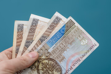 Polskie banknoty pln 200 i 500 złotych trzymane na rozmytym niebieskim tle - obrazy, fototapety, plakaty