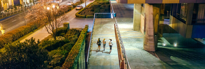 Unrecognizable group of young women friends runners training together on the city next to road at...
