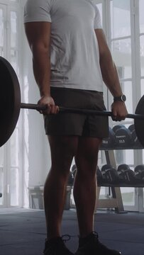 Determined young multiracial man doing squats while weightlifting with barbell at the gym