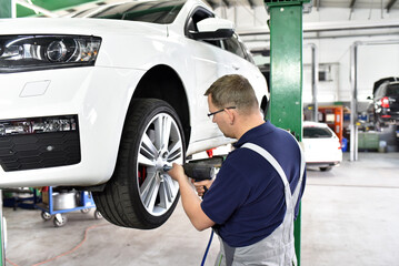 car mechanic changes the tires of the vehicle in the workshop