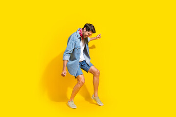 Fototapeta na wymiar Full size photo of good mood guy wear jeans jacket shorts in sunglass dancing at summer party isolated on bright yellow color background
