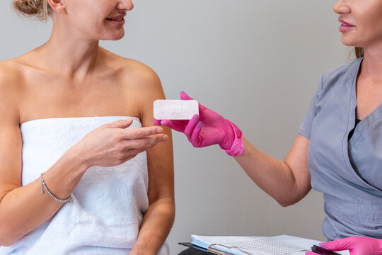 Beautician gives gift card to happy client. Close up of voucher for laser hair removal. Discount for cosmetology